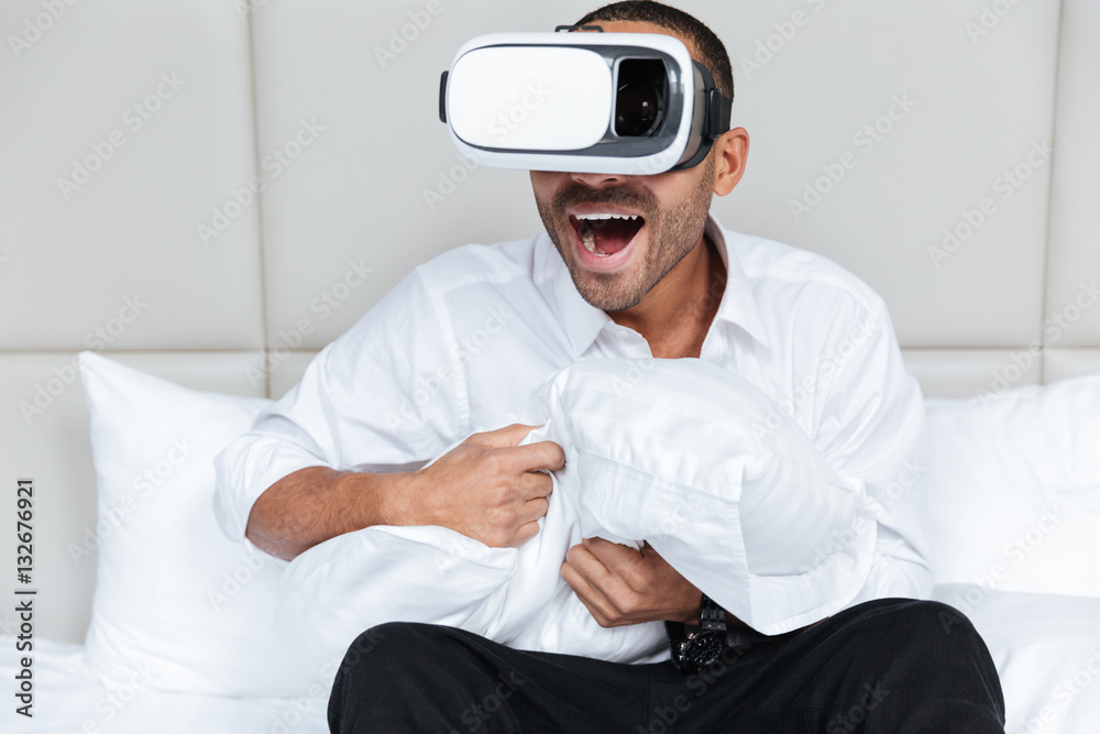 Young African man in virtual reality device on bed Young African man in virtual reality device on bed
