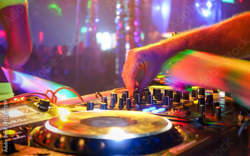 Close up of dj playing party music on modern cd usb player in disco club - Nightlife and entertainment concept - Defocused background with shallow depth of field and focus on buttons near mixing hand photo