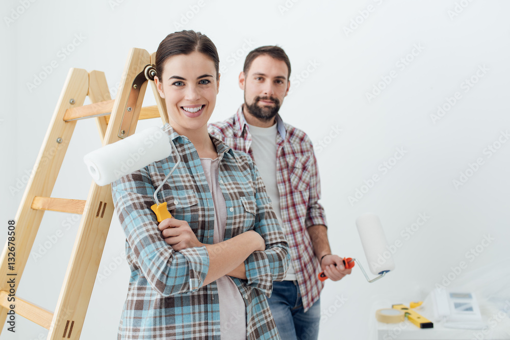 Happy couple painting their new home - obrazy, fototapety, plakaty 