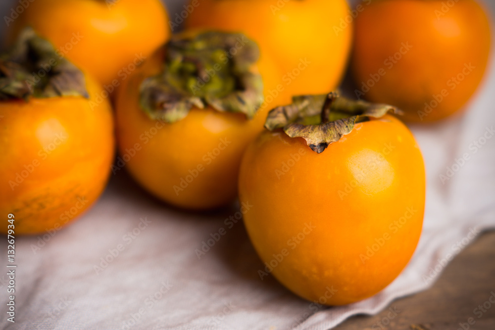 Fresh persimmon fruit on wooden table. Shallow depth of field. Fresh persimmon fruit on wooden table. Shallow depth of field.