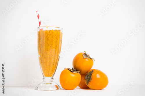 Persimmon smoothie with carrot and orange on wooden background