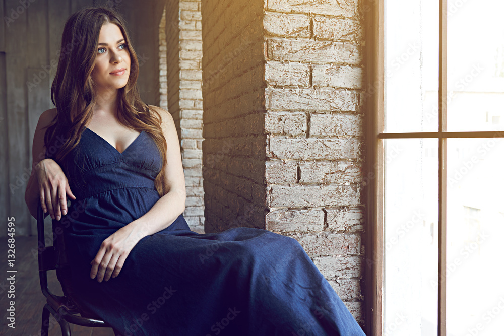 Fototapeta premium Portrait of young woman with long hair beside window.
