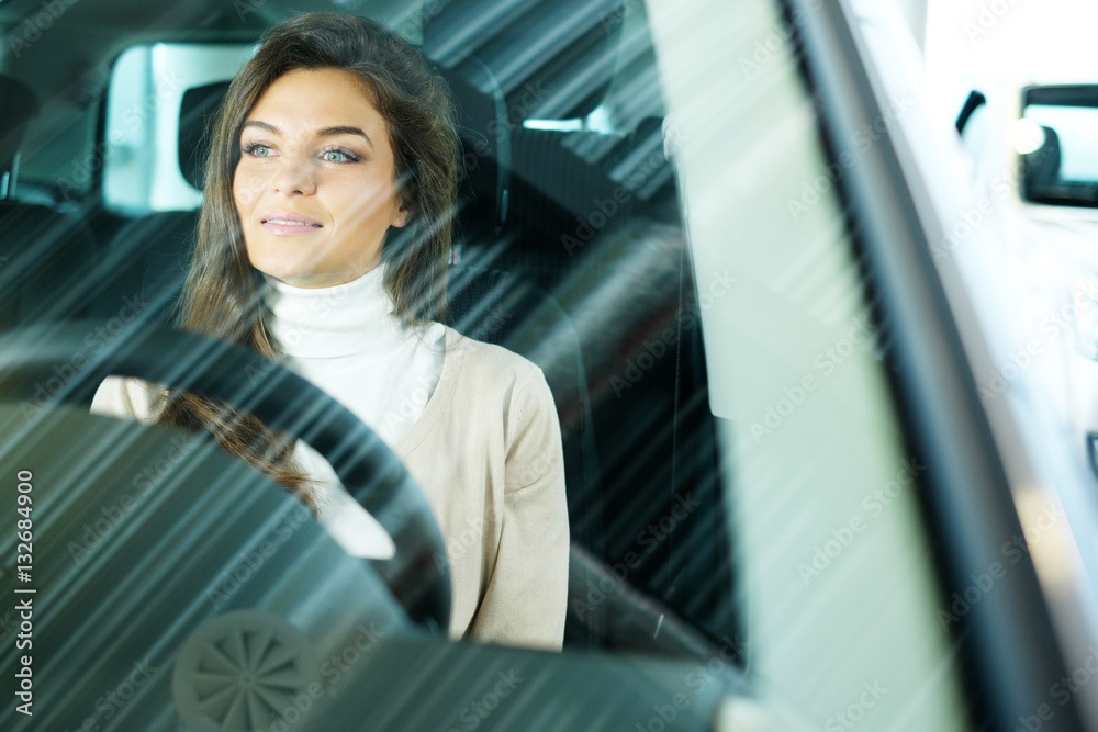 Beautiful young woman buys a car in the dealership saloon Beautiful young woman buys a car in the dealership saloon