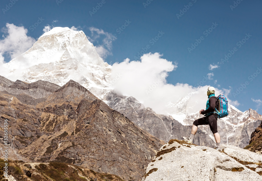 Man with Backpack staying on Rock in high Mountains