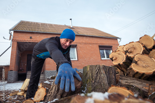 Man pulls out a log from the wood pile.