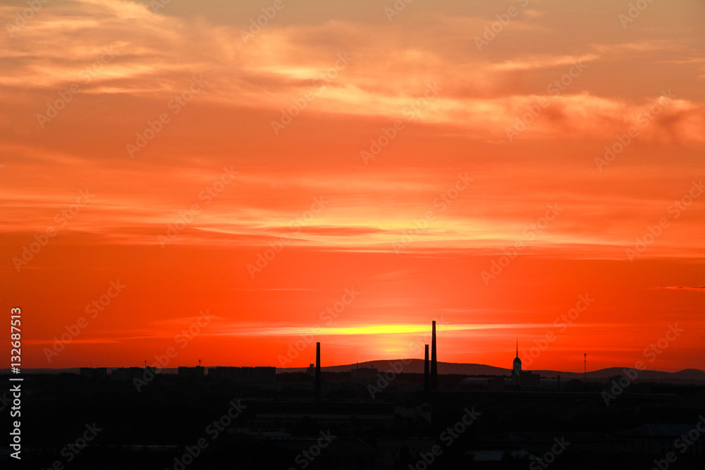 Cityscape at sunset. Silhouette of industrial city against evening colorful sky.