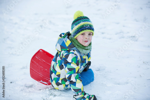 Cute child, boy, sliding with bob in the snow, wintertime
