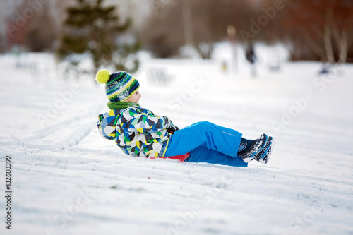Obraz na plátně Cute child, boy, sliding with bob in the snow, wintertime