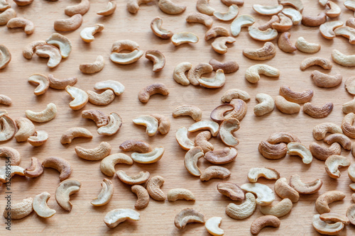 Roasted cashew nuts spread around wooden board.