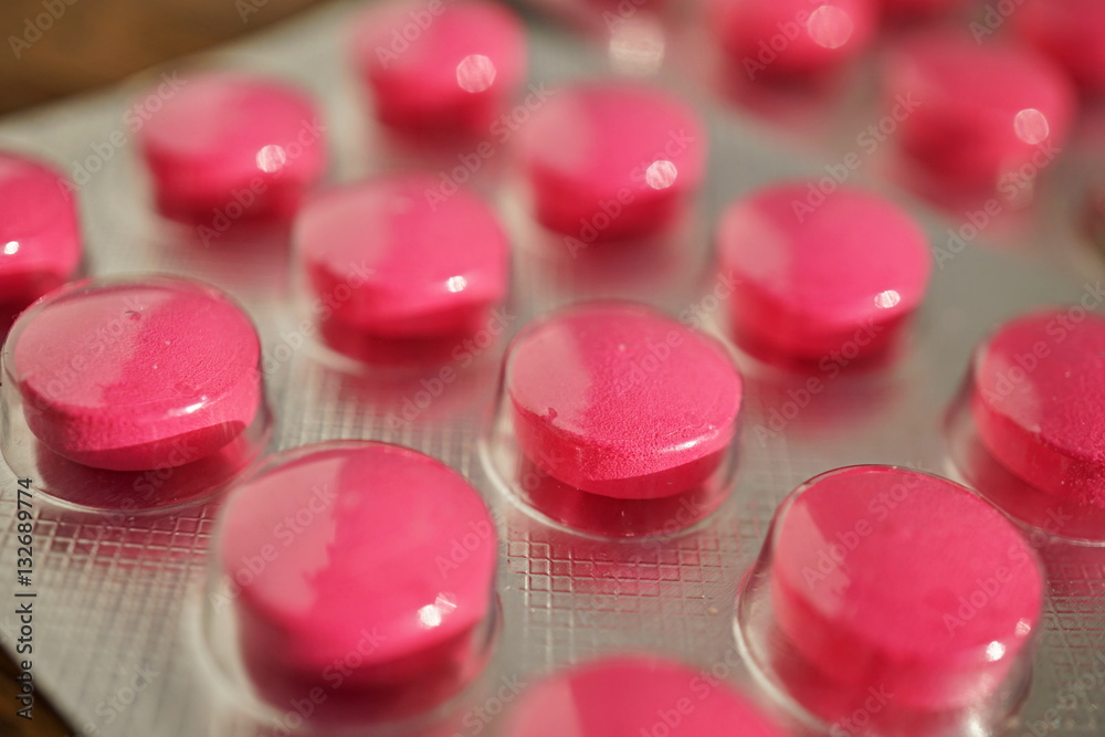 Rows of pink pills in the plastic tray as a symbol of modern medicine, medicaments and treatment Rows of pink pills in the plastic tray as a symbol of modern medicine, medicaments and treatment