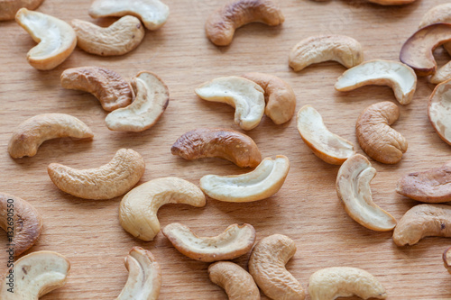Roasted cashew nuts spread around wooden board.