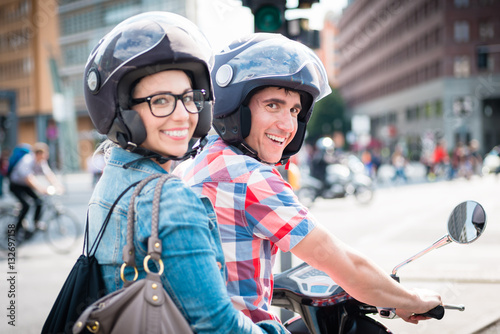 Lächelndes Mädchen mit Brille auf dem Sozius Sitz eines Motorrollers  photo