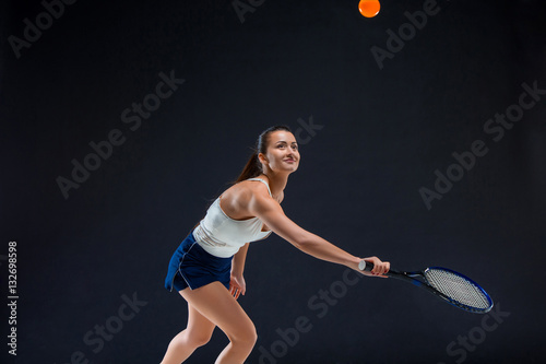Portrait of beautiful girl tennis player with a racket on dark background © master1305