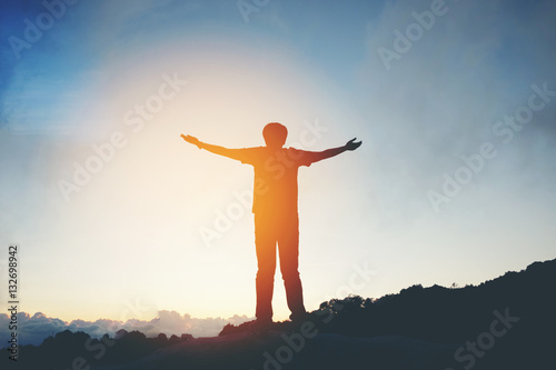 Silhouette Freedom man standing with raised arms and enjoying on