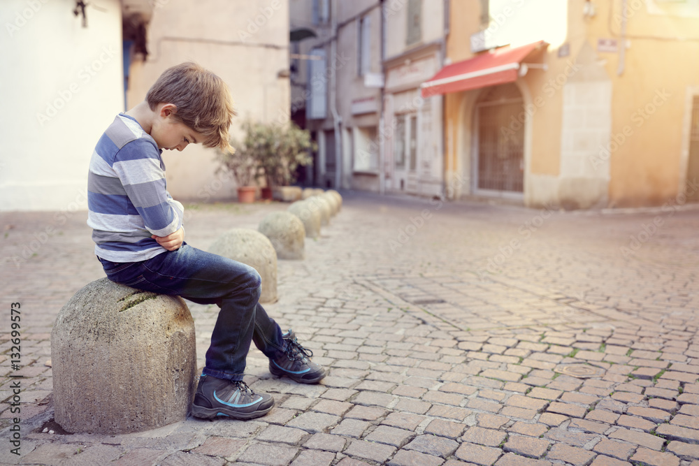 Lonely child sitting on a street corner Lonely child sitting on a street corner