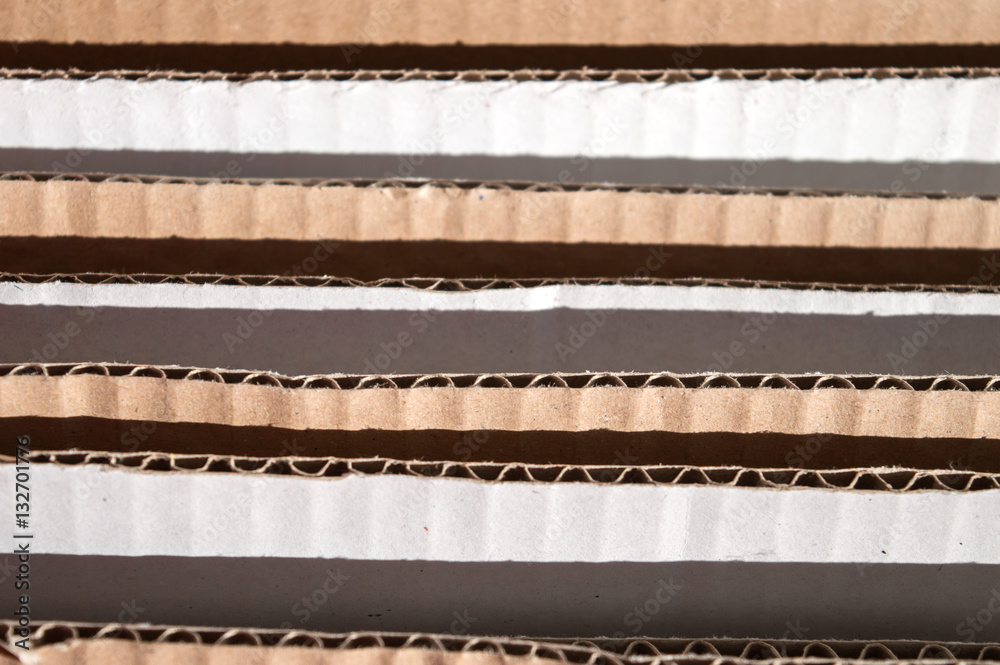 Obraz premium Texture of layered brown cardboard side. Folded cardboard boxes. Wavy paper texture on sunlight with copy space.