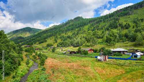 Old wooden houses with gardens in valley of a small stream. photo