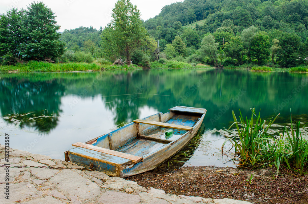 Wooden boat at the riverbank, in the early evening. Una river in Bihac - Bosnia and Herzegovina