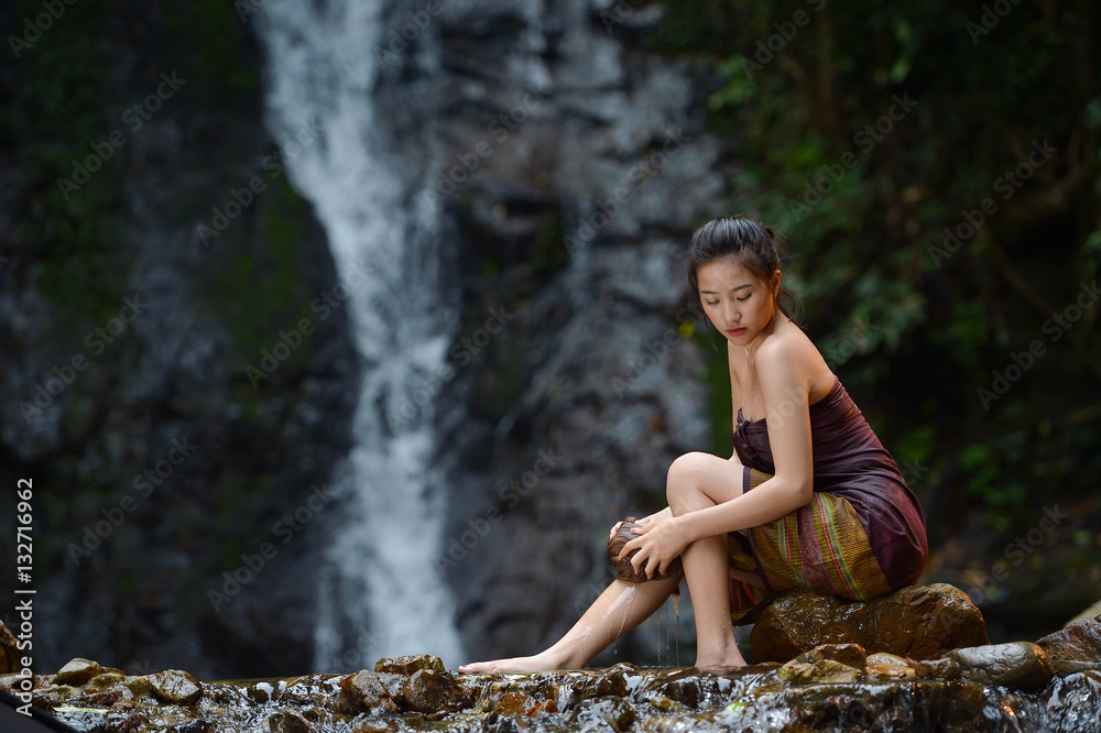 Asian woman wearing traditional thai take a baht on during sunset