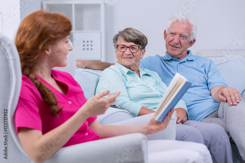 Caregiver reading to elderly couple