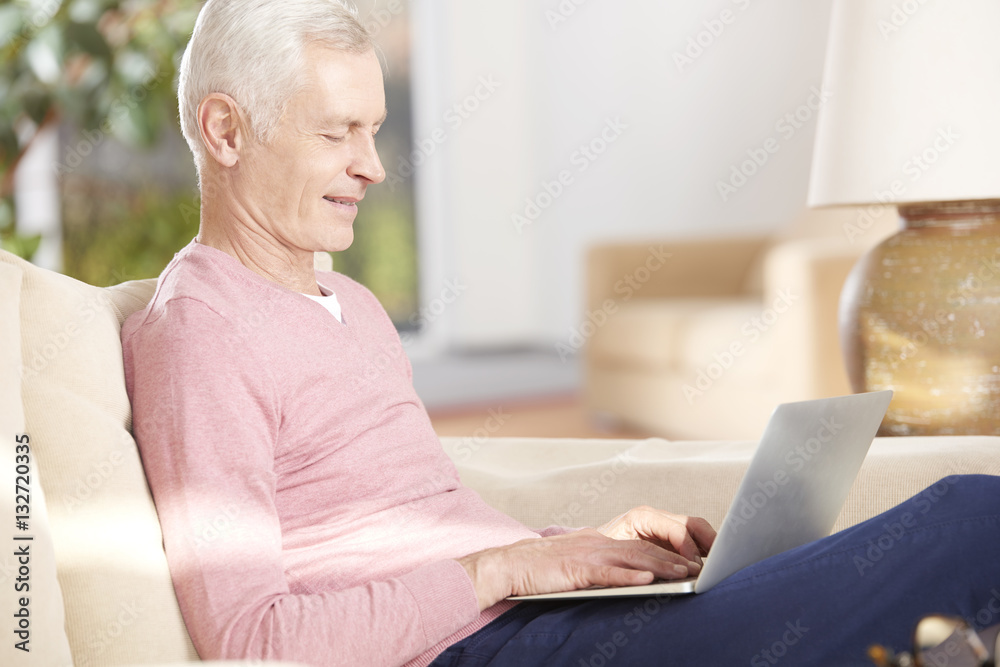 Shot of a senior man using his laptop and working from home while sitting on living room. Shot of a senior man using his laptop and working from home while sitting on living room.