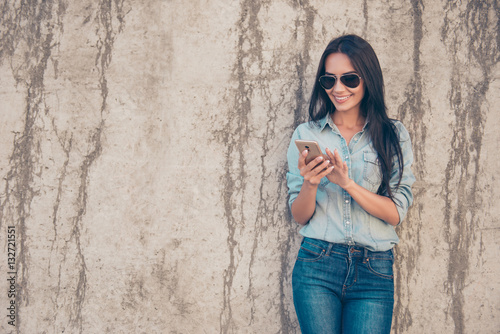 Happy young woman in glasses using her smartphone for communicat