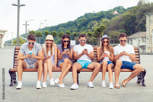 successful young  people in glases  using their smartphone and c