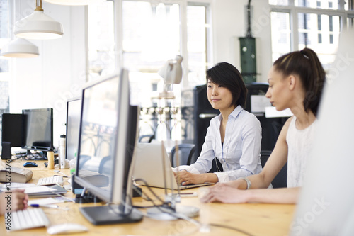 Japanese woman working with mixed race colleague in an informal office