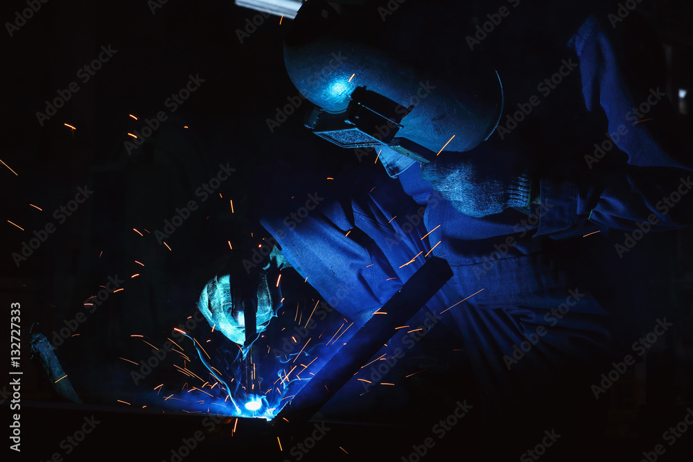 Welder of Metal Welding with sparks and smoke in factory