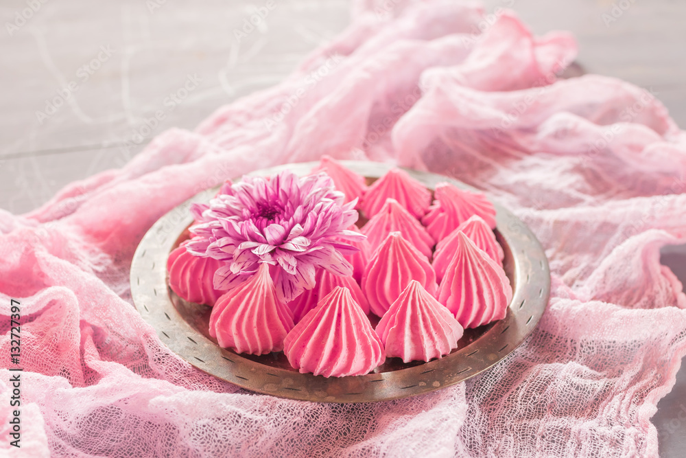 Air meringue with fresh flowers lie on a metal dish on a pink v Air meringue with fresh flowers lie on a metal dish on a pink v