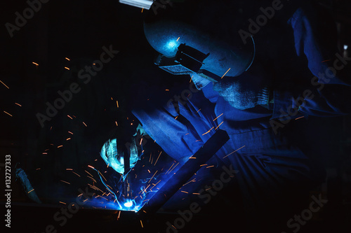 Welder of Metal Welding with sparks and smoke in factory