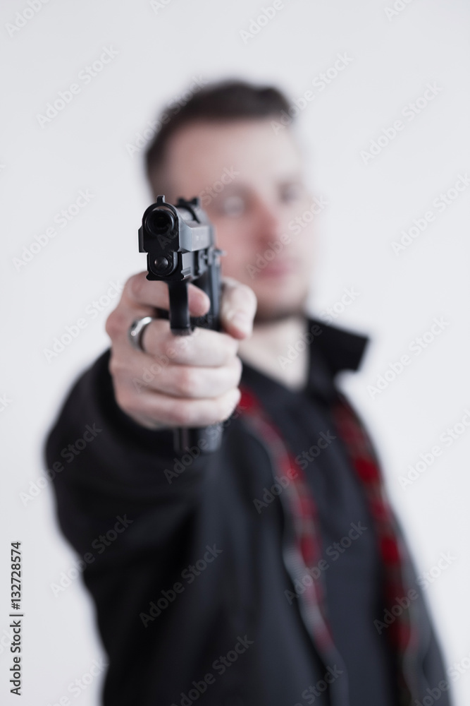 Closeup of focused young man standing and aiming with gun Closeup of focused young man standing and aiming with gun