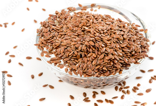 Flax seeds in transparent bowl on white background
