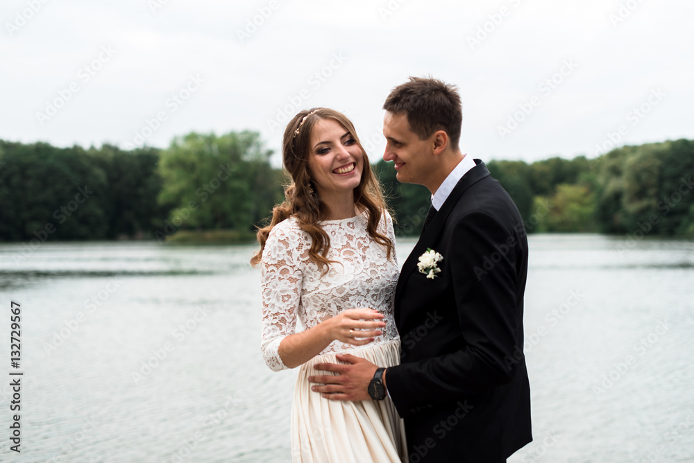 happy bride and groom at a park on their wedding day near the lake