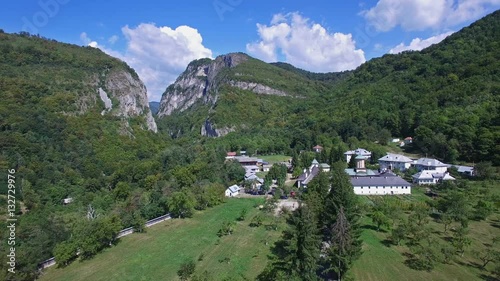 Aerial view of Polovragi Monastery surrounded by green hills, Romania, panning photo