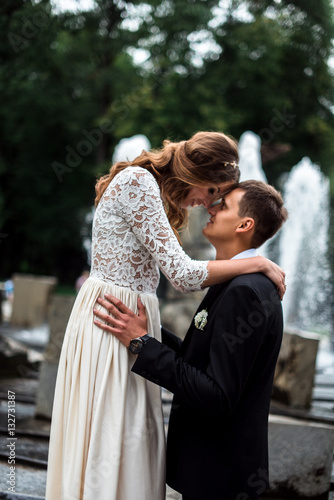 Bride and groom kissing with the fountain on the background
