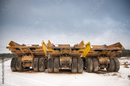 Three yellow empty trucks in the quarry.