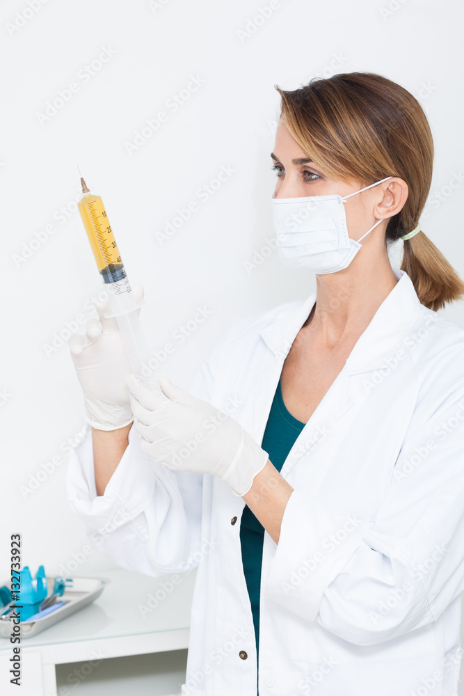 femme infirmière en blouse blanche avec un masque chirurgical et une grosse  seringue Stock Photo