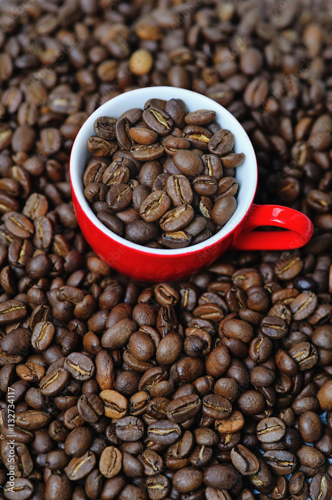 Red cup full of coffee beans on coffee background
