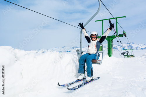 Happy female skier riding a lift.
