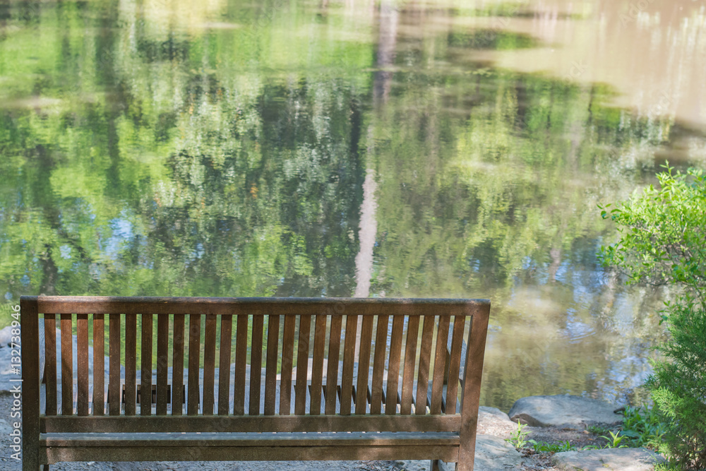 Peaceful sitting spot overlooking still, reflective water. Bench. Seat.