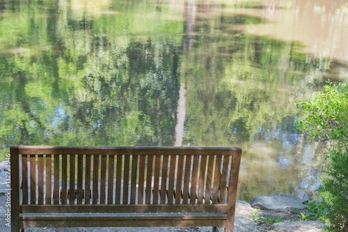 Obraz na płótnie Peaceful sitting spot overlooking still, reflective water. Bench. Seat. w salonie