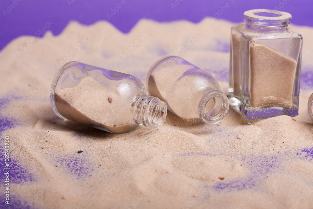 garrafas pequenas com areia em fundo roxo