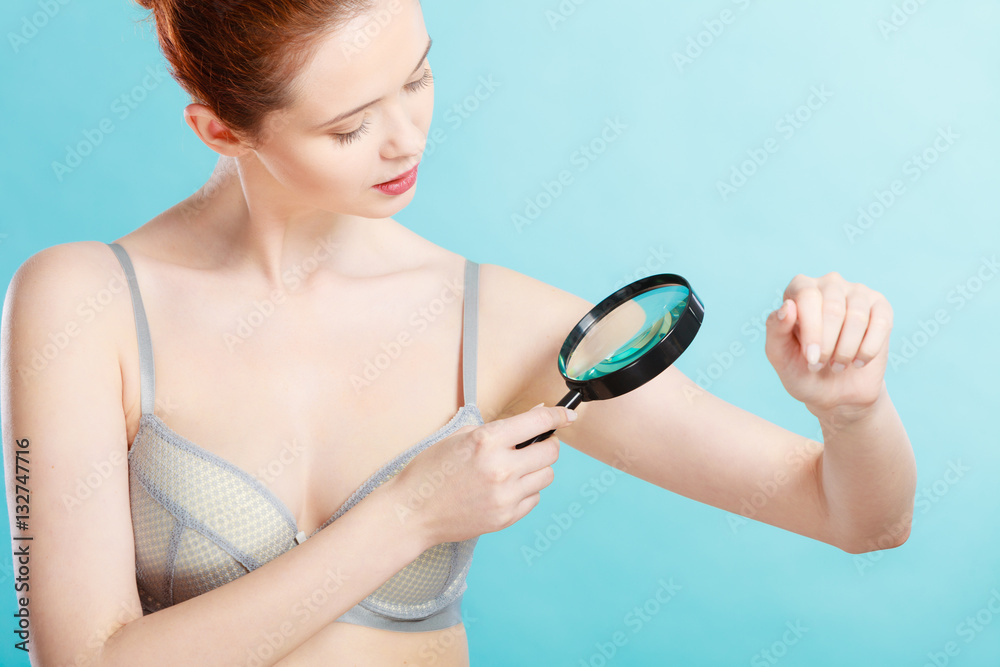 Woman using magnifying glass to examine her moles skin Woman using magnifying glass to examine her moles skin