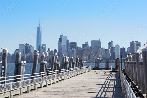 New York city skyscrapers and empty pier with seagulls  sunlight