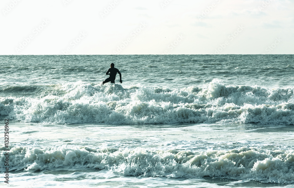 Single alone surfer surfs in cold sea at English coast