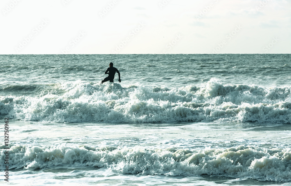 Single alone surfer surfs in cold sea at English coast Single alone surfer surfs in cold sea at English coast