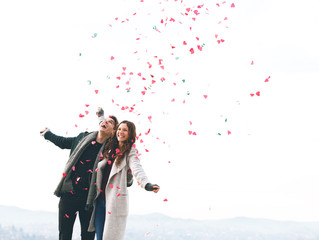 Cute young couple in love, outdoors with hearts falling
