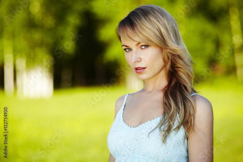 Beautiful young blond woman outdoors. Sunny day. Nature summer background. Outside close-up portrait of beautiful young happy woman with fresh and clean skin