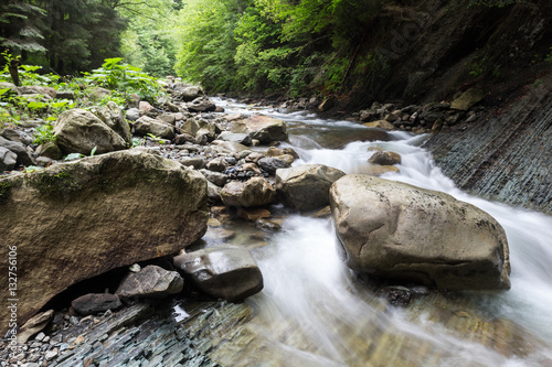 Fotografie Cascade falls over old plum river with rocks in the forest